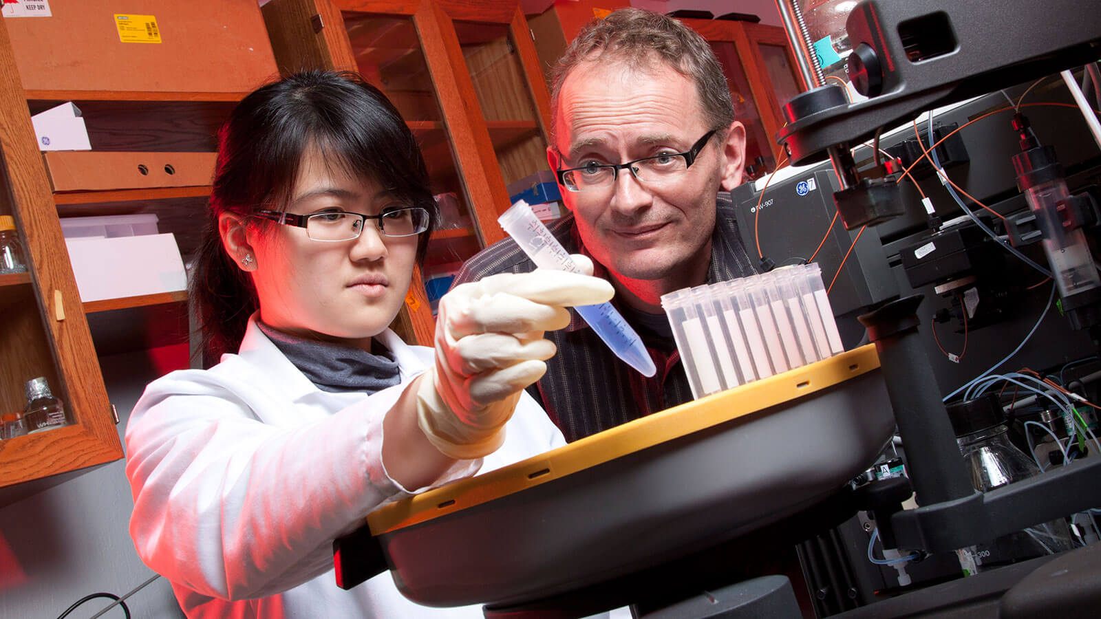 Student and faculty member look at pipette in lab