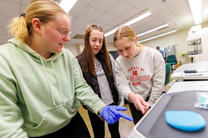 Kiara Polifka (from left) Quinn McClatchey, and Emily Kanitz study the image taken by the GelDocGo machine that visualizes the results of an experiment where students cut DNA with enzymes and now get to see how many pieces their enzymes cut.