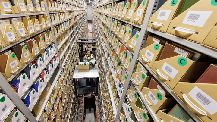 Several stories above the ground, Josh Caster, Archives Manager for University Libraries, retrieves a book stored in the Library Depository Retrieval Facility on East Campus.