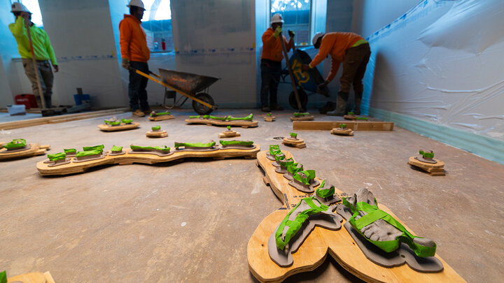 Employees from Stephens & Smith Construction pour wheelbarrows of cement around a 3D printed replica of an incomplete Menoceras arikarense fossil – a small, extinct rhinoceros found in Nebraska fossil beds. The replica was printed by Frontier Tech Lab at the Nebraska Innovation Studios and will be part of a new fossil dig in the redesigned Marx Science Discovery Center in Morrill Hall.