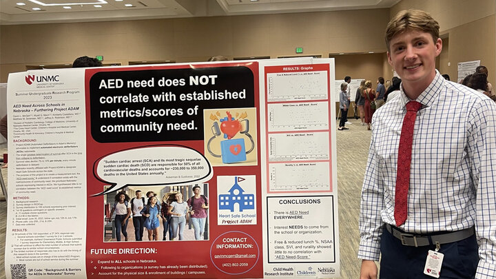 Gavin McGerr standing next to a board filled with research he helped conduct